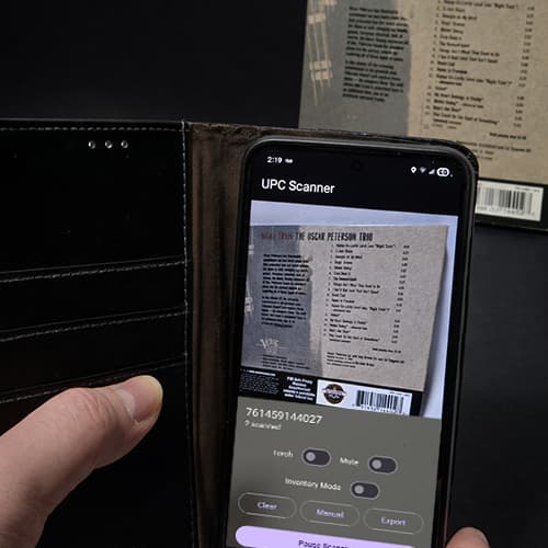 Hand scanning a CD barcode with the M Media UPC Scanner app on an Android phone